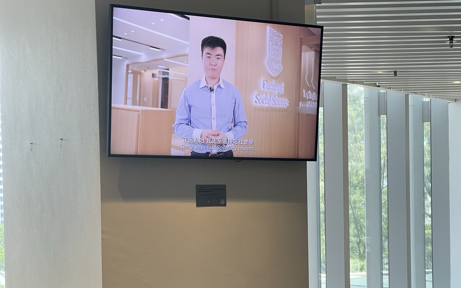 A U-Vision screen mounted above the study seating on the first floor of Chi Wah Learning Commons, beside its glazed facade