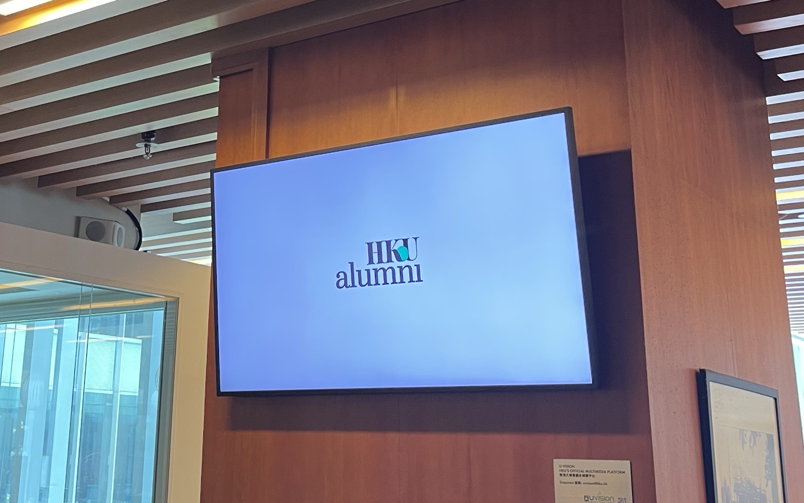 A U-Vision screen on the timber-clad pillar on the second floor of Chi Wah Learning Commons, under its slatted ceiling