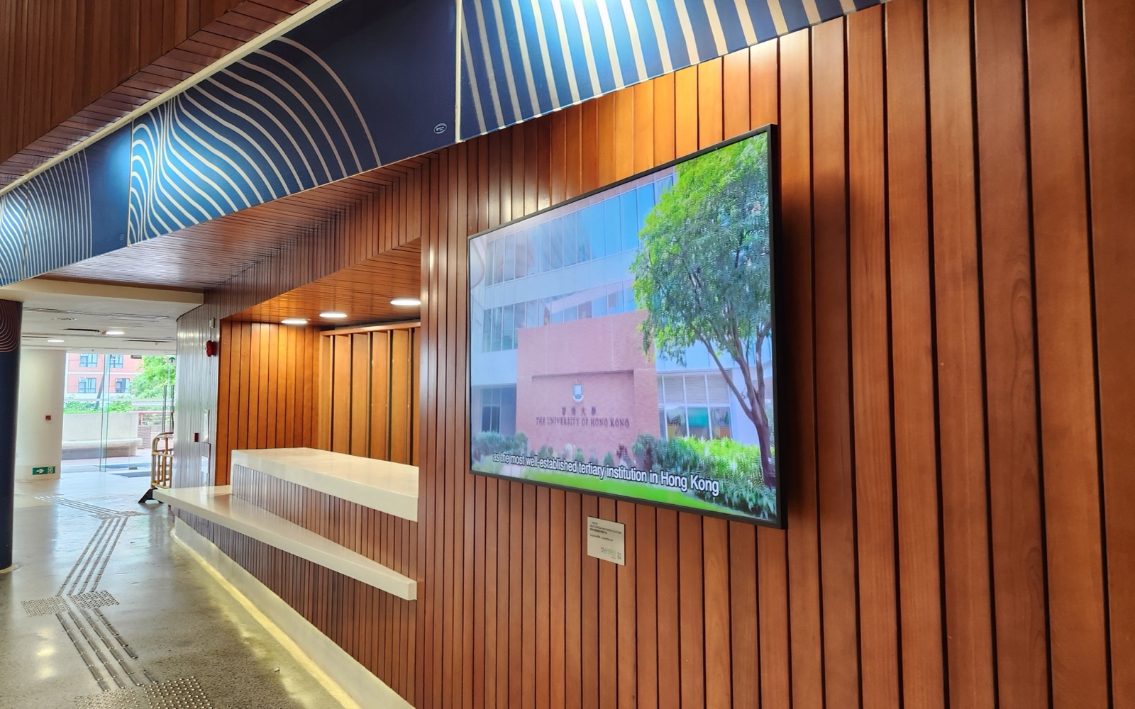 A U-Vision screen set into the timber-slat wall on the fourth floor of the Chong Yuet Ming Amenities Centre