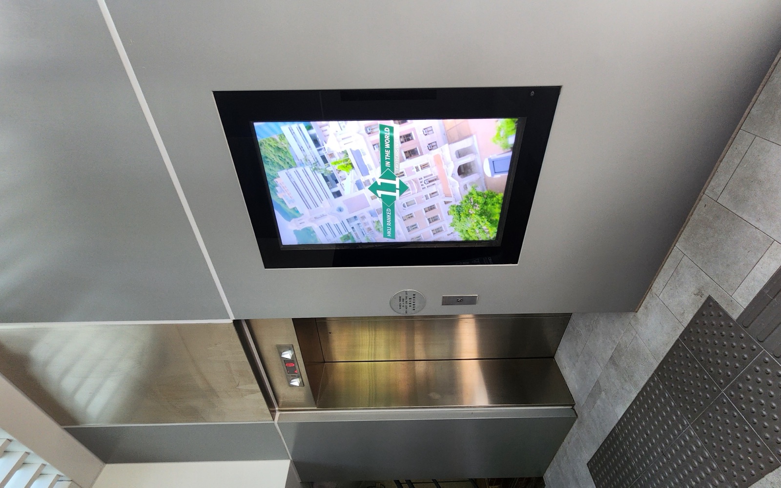 A U-Vision portrait screen set into the wall above the lift lobby in East Gate