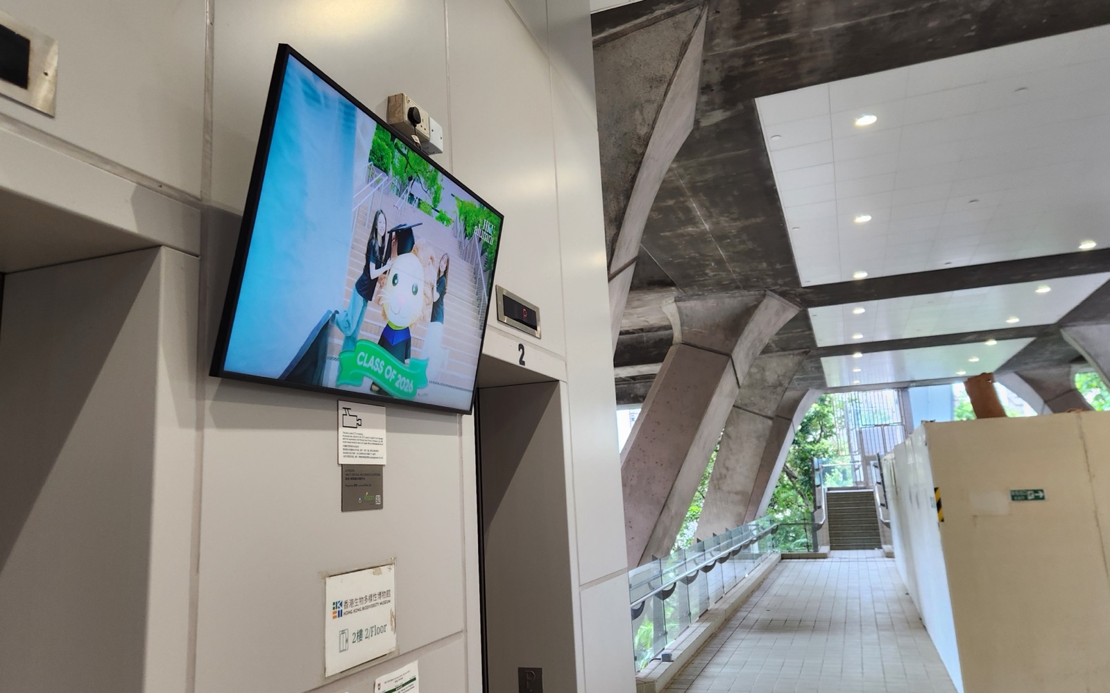 A U-Vision screen mounted on the corridor wall inside the Kadoorie Biological Sciences Building