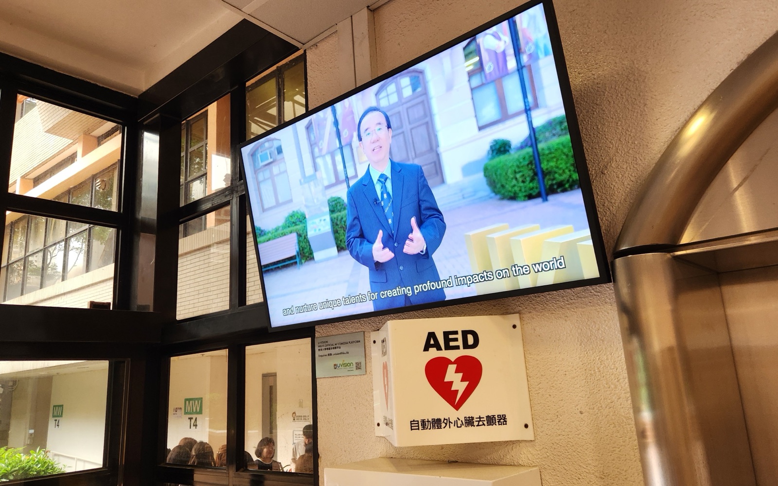 A U-Vision screen mounted on the corridor wall of the Meng Wah Complex, beside the AED station