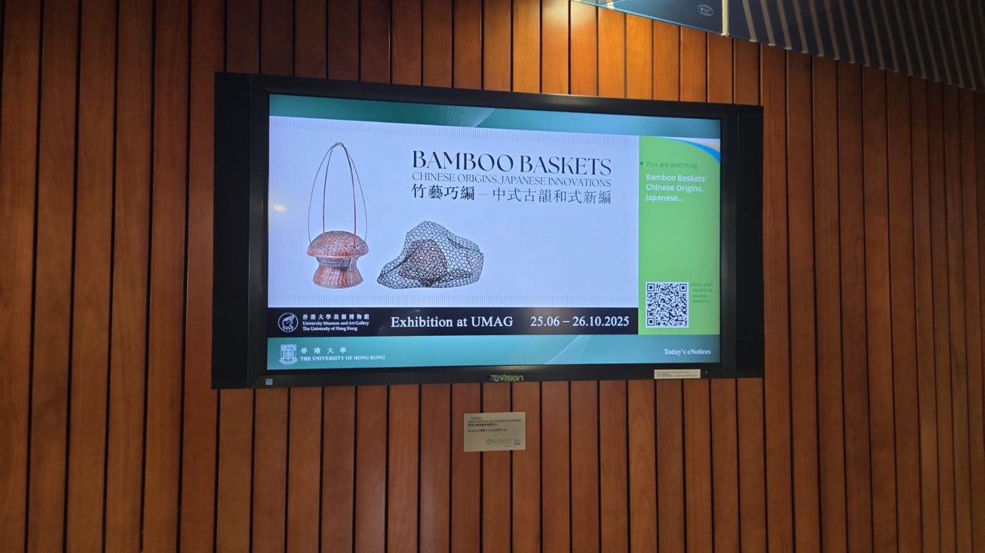 A U-Vision digital screen mounted on a campus wall showing an HKU museum exhibition promotion