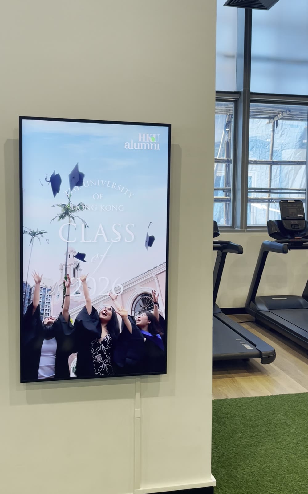 A U-Vision portrait screen on the gym wall at HKJC Village 4, beside the treadmills