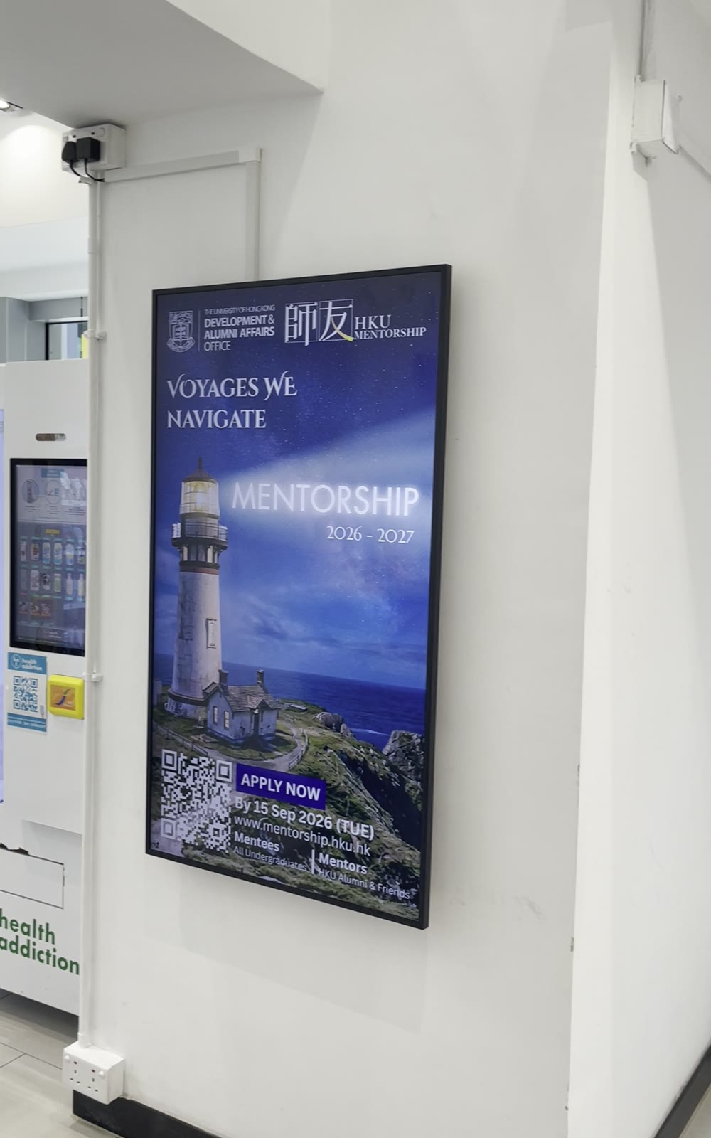 A U-Vision portrait screen on the wall beside the vending machines at HKJC Village 4